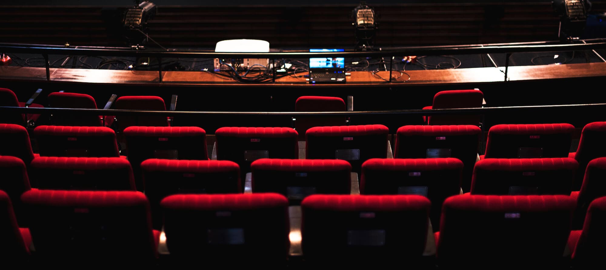 Empty theater seats facing a control booth with equipment, preparing for a performance.