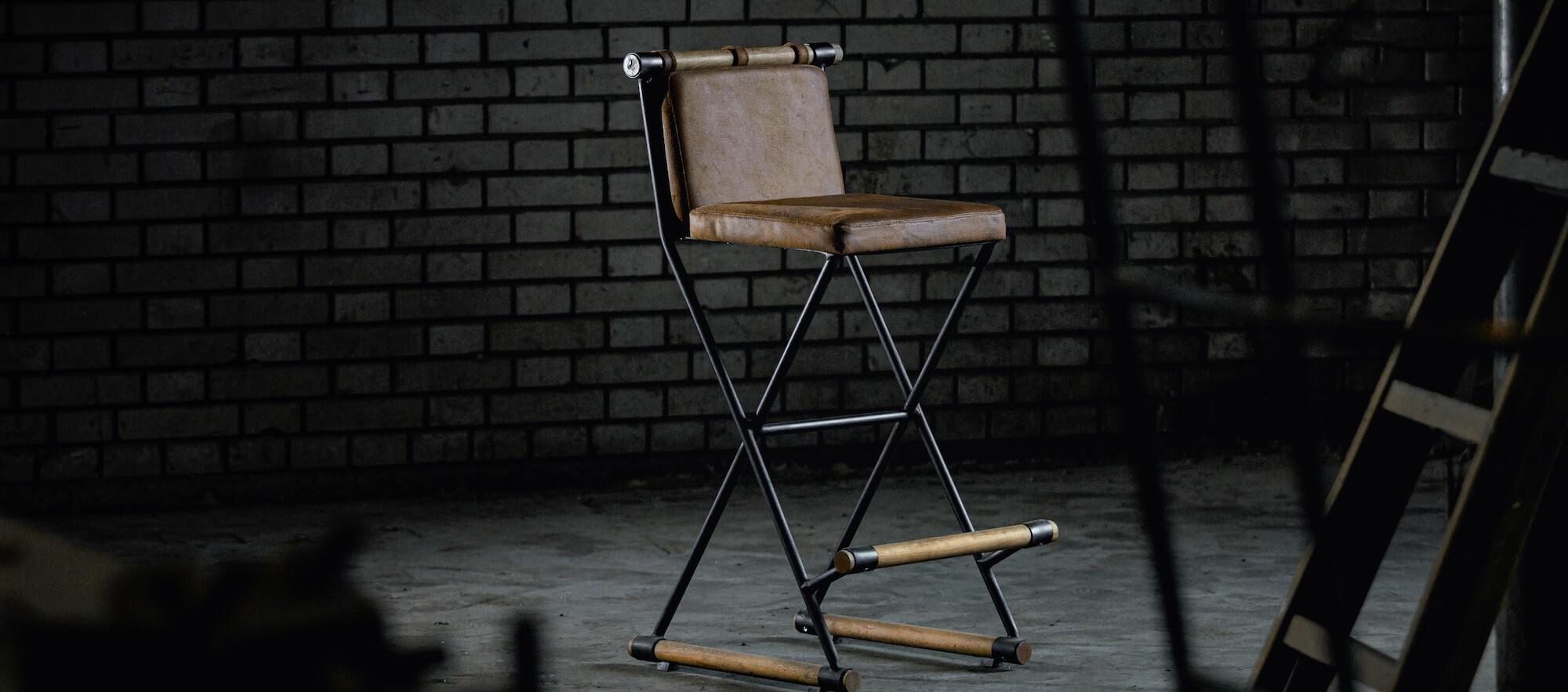 Empty director’s chair in a dimly lit studio with a brick wall background.